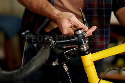 Buy stock photo Hands, maintenance and handyman fixing bicycle in garage for repairs with equipment or tools. Small business, service and mechanic with tightening mechanical part for improvement on bike at workshop.