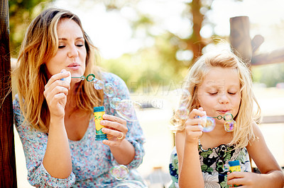 Buy stock photo Outdoor, bubble and mother with girl, playing and bonding together with happiness. Family, parent and mama in backyard, child or daughter with smile, summer fun or liquid soap with break, kid or game