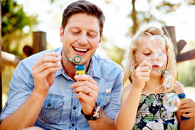 Buy stock photo Father, child and blowing bubbles at park for sensory stimulation, creative imagination or freedom. Family fun, dad and girl kid with soap toy in nature for bonding activity and childhood development