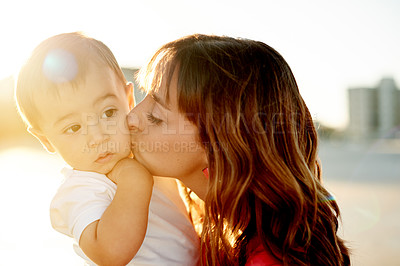 Buy stock photo Mother, baby and kiss at beach with hug, flare or love for bonding on holiday. Woman, boy child with affection or holding kid outdoor, sunshine and adventure with travel in Australia for summer