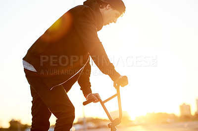 Buy stock photo Balance, city and sunset with man on bicycle for adrenaline, exercise or extreme sports outdoor. BMX, flare and training with bike rider on street in urban town for action, hobby or skill practice