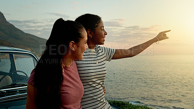 Buy stock photo Travel, lesbian couple and view on beach at car with pointing, sightseeing and road trip pause. Sunset, hug and lgbt women at ocean for holiday adventure, exploring environment and bonding together
