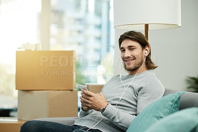Buy stock photo Man, phone and boxes in new home, portrait and listen to music with earphones, smile or web chat in lounge. Person, smartphone and scroll with mobile app, streaming subscription and property in USA