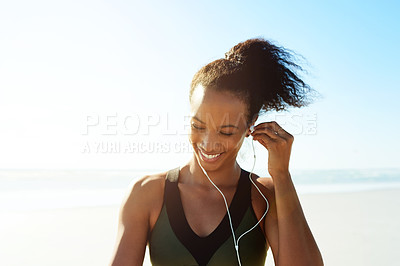 Buy stock photo Fitness, break and woman with earphones at beach for exercise, music or workout podcast. Smile, runner and athlete with tech for marathon training, space and streaming audio or getting ready by ocean
