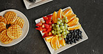 Above, food and breakfast spread on table with waffles, homemade meal and colorful presentation. Fresh, nutrition and fruit platter on counter for brunch arrangement, appetizing and weekend morning
