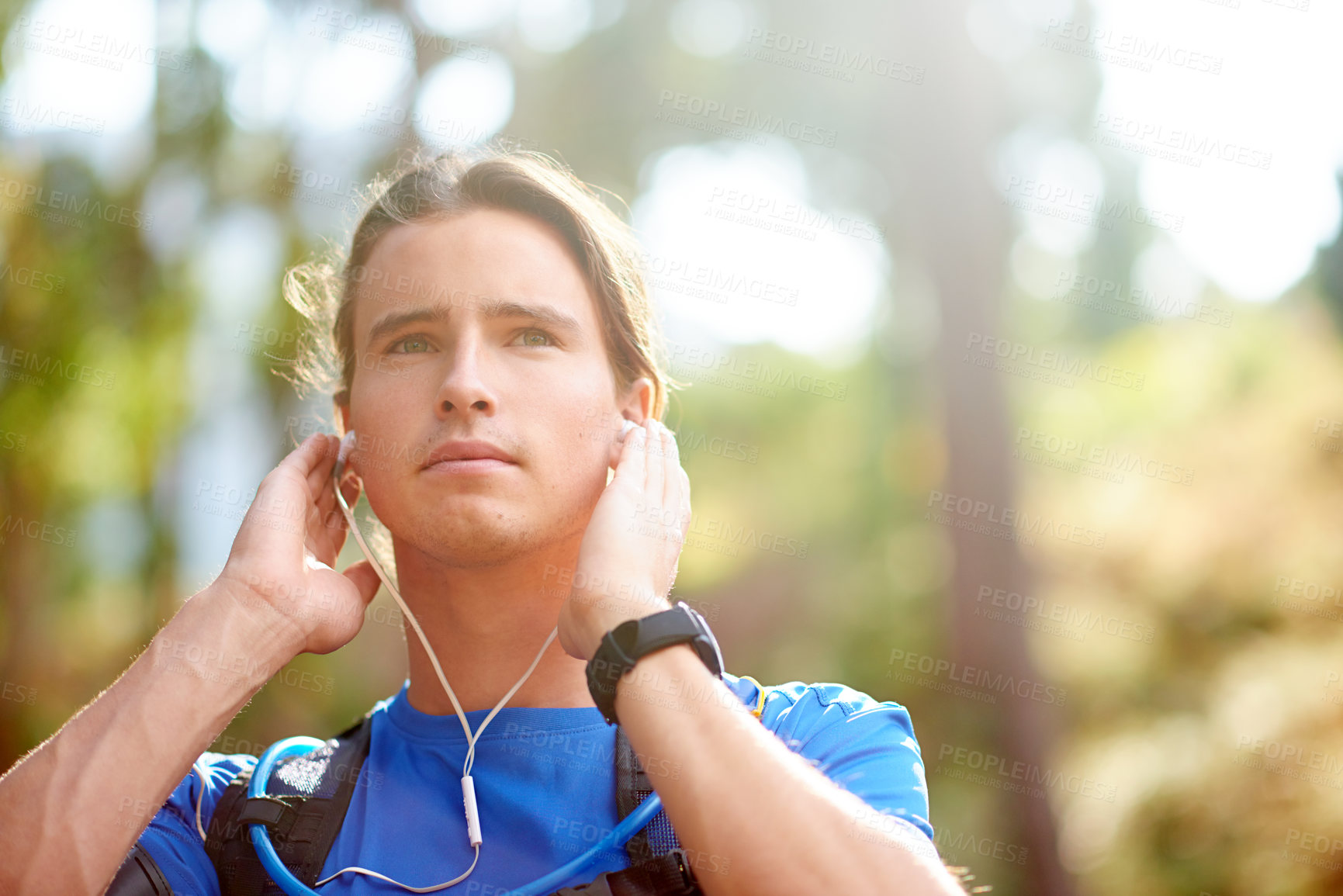 Buy stock photo Man, runner and earphones for fitness in forest, outdoor and break with training, space and music. Person, streaming and audio with thinking in woods by trees for trail running for exercise in USA