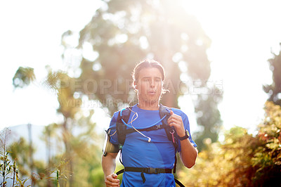 Buy stock photo Fitness, man and running with earphones in forest for marathon playlist, breathing exercise and cardio music. Runner, sunlight and backpack on nature trail for workout performance or training podcast