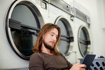 Buy stock photo Washing machine, phone and man at laundromat with communication, contact or connectivity. Cellphone, social media and male person by equipment with online networking for chores, laundry or basket.
