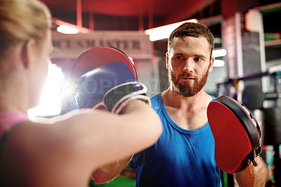 Buy stock photo Boxing, training or woman with coach for fighting exercise, strong punch or self defense gym. Pads, learn or boxer in sports practice for teaching technique or fitness workout with personal trainer