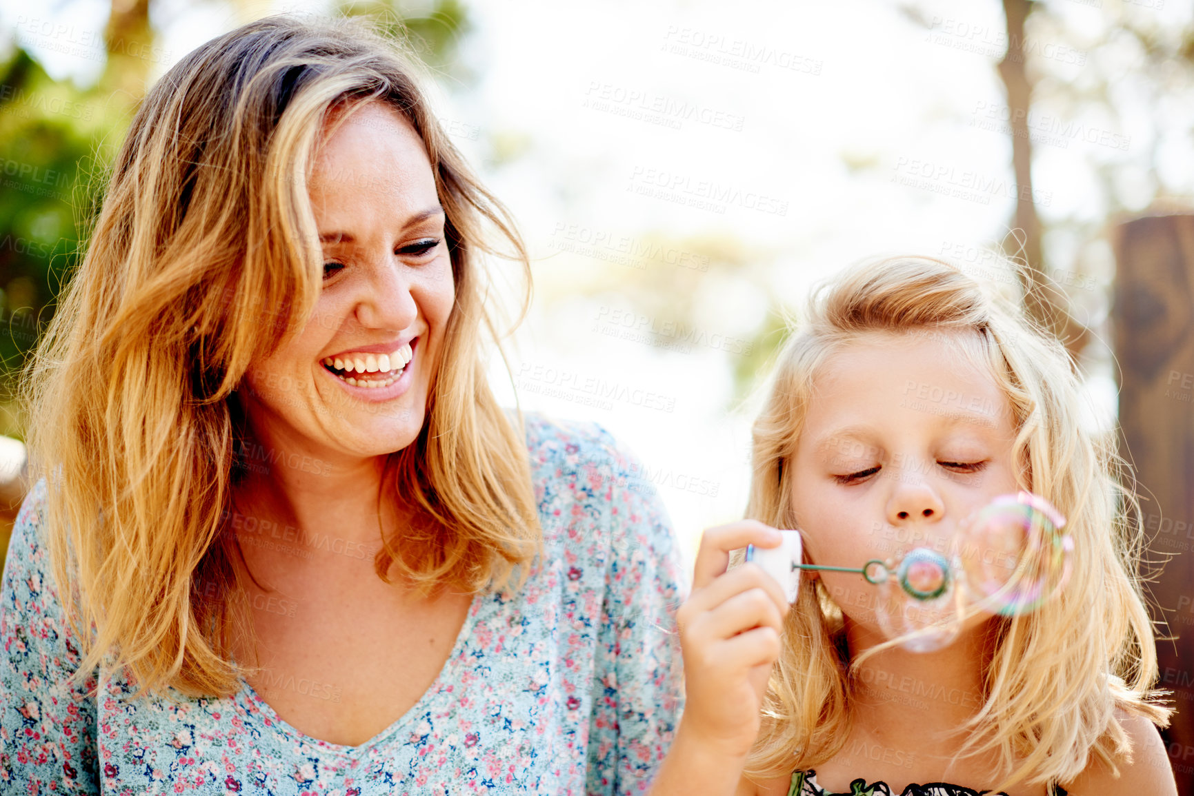 Buy stock photo Blowing bubbles, mother and girl in park for bonding, together and outdoor for fun. Soap toy, child and woman in garden with summer, holiday and daughter with care and play in nature for weekend