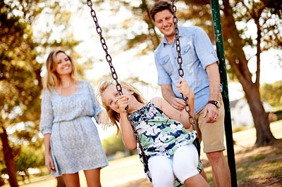 Buy stock photo Parents, girl and happy on swing at park for playing together, freedom or holiday portrait. Family fun, people or riding on playground equipment for bonding, sensory stimulation or childhood memory