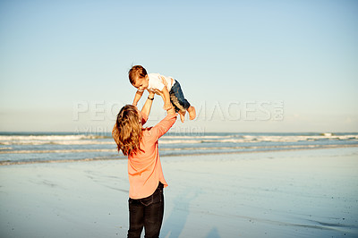 Buy stock photo Beach, bonding and mom holding child for playing, care and connection together by ocean. Love, happy and mother lifting boy kid in air for fun by sea water on summer vacation, getaway or weekend trip