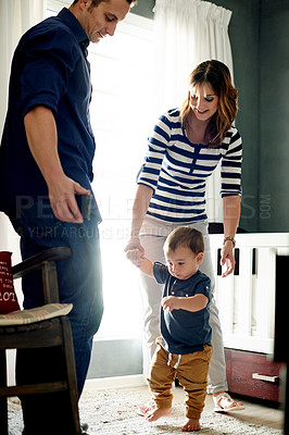 Buy stock photo Parents, home and teaching toddler to walk with love for growth, development or support. Mom, learning and boy with first steps for balance, mobility movement and help for child with bonding together