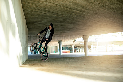 Buy stock photo Man, bike and jump stunt in city with challenge, talent or action outdoor for extreme sports. Skill, trick or wheelie with person, athlete or ride for performance, bicycle and energy in urban park