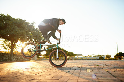 Buy stock photo Man, bike and stunt in city with talent at sunset, trick or performance for extreme sports outdoor. Skill, action and male athlete on bicycle for fitness, urban cyclist challenge or rider by space