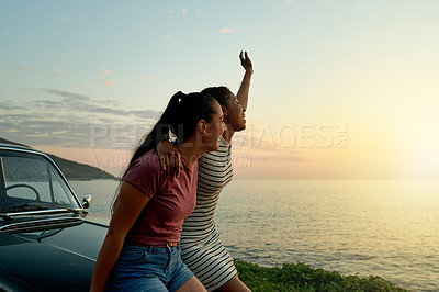 Buy stock photo Shot of two happy young women enjoying a road trip