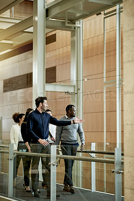 Buy stock photo Walking, team and pointing with business people in hotel for meeting, conference expo and partnership. Discussion, collaboration and seminar event with employees on bridge of convention center