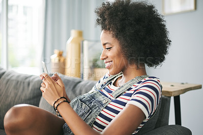 Buy stock photo Phone, smile and text message with woman on sofa in living room of home for online post or update. App, communication and relax with happy African person in apartment for download or mobile chat