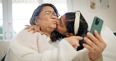 Buy stock photo Grandma, granddaughter and kiss with phone in home for love, family bonding or care together. Grandmother, grandchild and affection with technology for weekend visit, memory or free time in house