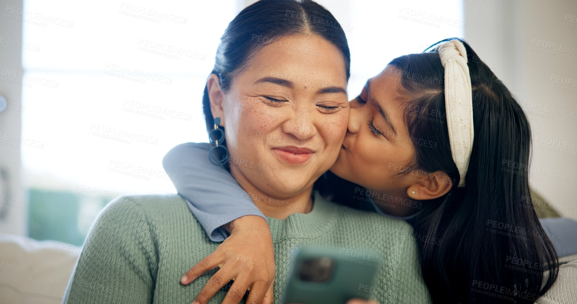 Buy stock photo Phone, mom and child on sofa with kiss, hug and love connection for social media browsing. Asian family, happy mother and kid in home with affection, healthy relationship or online reels with embrace