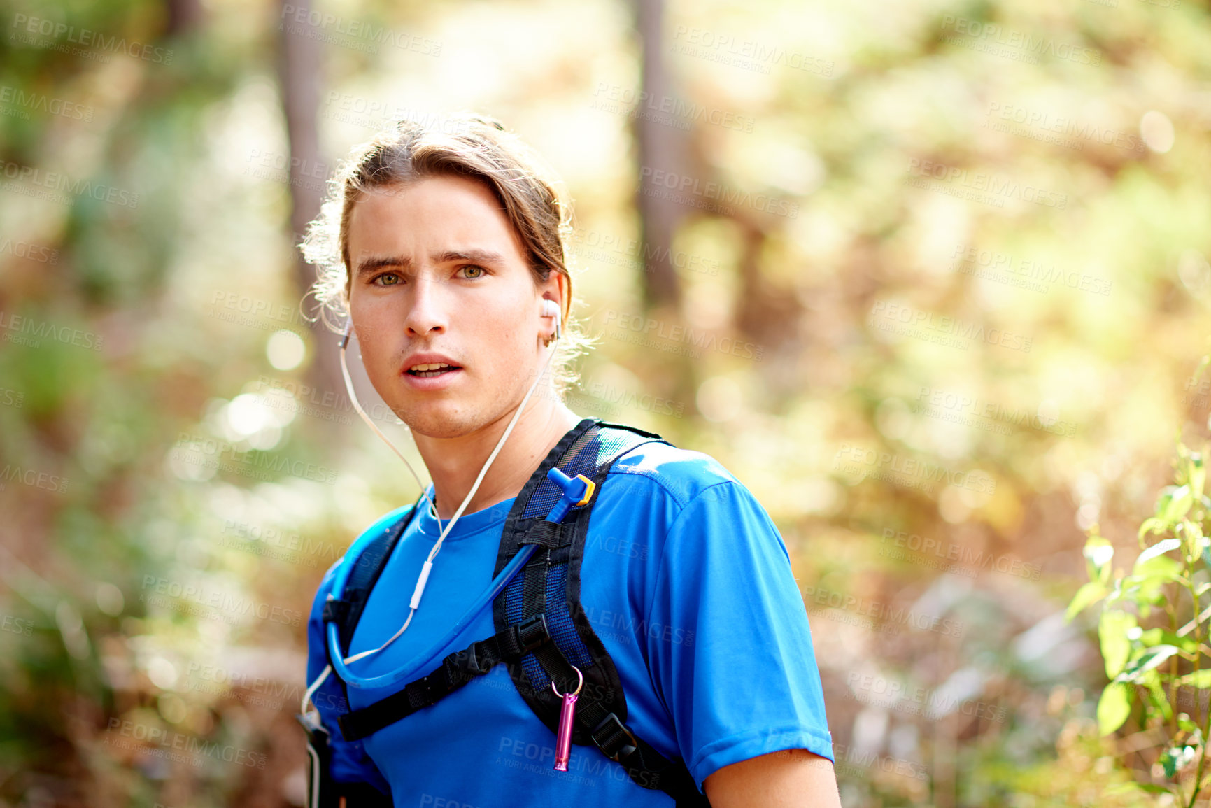 Buy stock photo Portrait, man and runner with earphones in nature for listening to music, fitness podcast and training. Athlete, person and streaming audio for exercise, sports workout or marathon practice in forest