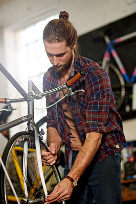 Buy stock photo Man, bicycle and repair tyres at garage with services, equipment and wheel alignment at small business. Person, technician and bike mechanic with low angle, safety check and inspection at workshop