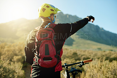 Buy stock photo Bike, pointing and sports with man in mountains for outdoor adventure, direction or training. Back, exercise and fitness with person cycling in nature for challenge, competition or performance hobby