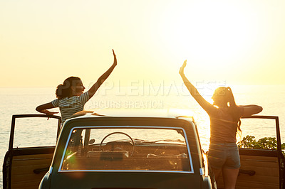 Buy stock photo Shot of two happy young women enjoying a road trip