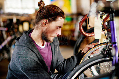 Buy stock photo Bicycle, repair and man in shop, mechanic or maintenance of eco friendly transport and entrepreneur. Wheel, inspection and person with bike in garage, technician and restoration of tire in workshop