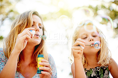 Buy stock photo Blowing bubbles, mother and child in park for bonding, together and outdoor for fun. Soap toy, girl and woman in garden with summer, holiday and daughter with care and play in nature for weekend