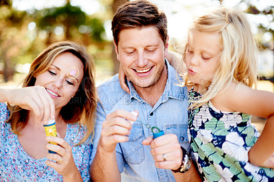 Buy stock photo Happy, family or child blowing bubbles in nature, bonding together or playing for connection. Smile, parents or daughter outdoor with summer activity for fun, joy or childhood memory on weekend break