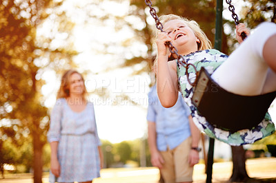 Buy stock photo Happy, playground and child at park with swing in air, parents and laugh for fun childhood memories. Smile, nature and girl outdoor with people, connection and playing for family bonding together.