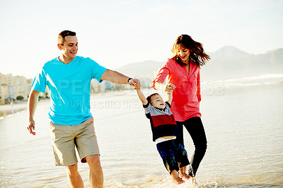 Buy stock photo Swing, waves and parents with child at beach for playing, bonding and relax outdoor on holiday. Family, happy and playful dad, mom and kid by ocean for adventure, vacation and holding hands in nature