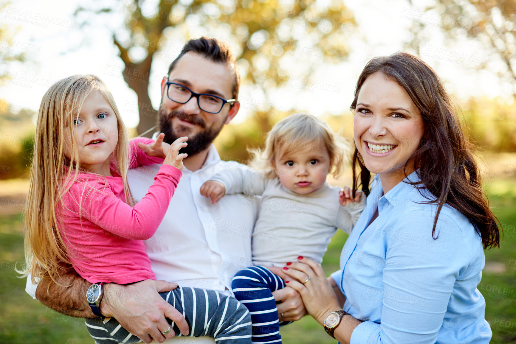Buy stock photo Parents, children and happy in portrait at park with bonding, care and excited with flare in nature. Family, people and kids in garden, summer or smile outdoor with love for relationship in Spain