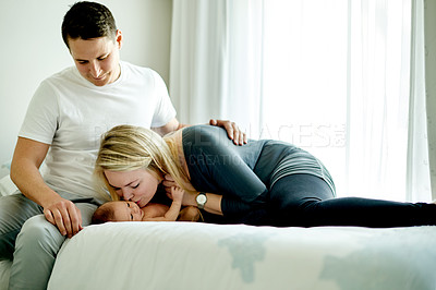Buy stock photo Happy parents, baby and kiss on bed in home for love, touch or bonding with care in morning. People, mother and father with infant child, comfort or affection with newborn in nursery at family house