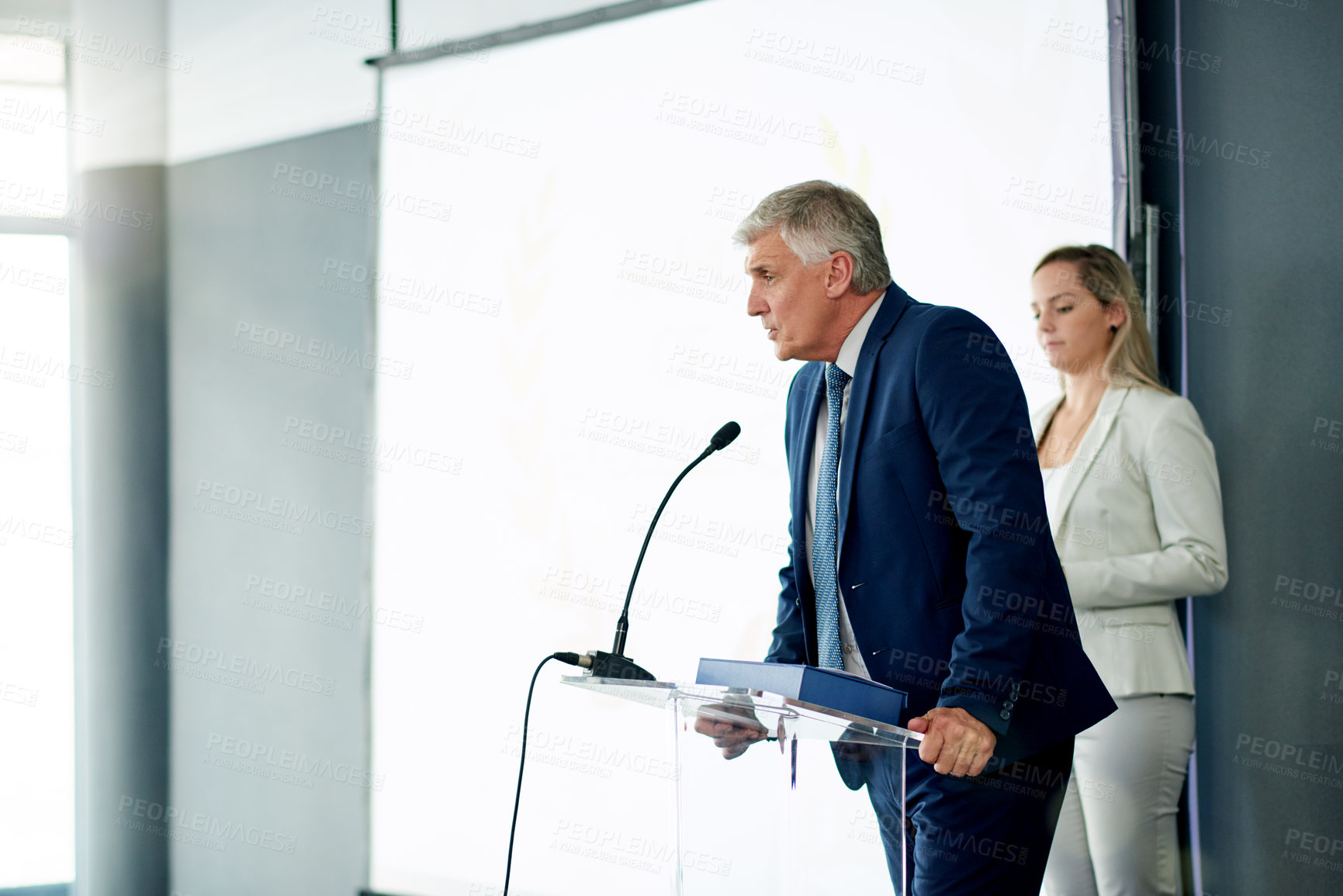 Buy stock photo Mature businessman, presentation and talk at seminar with microphone, insight and info at company. Person, leader and speaker on stage, event and speech for announcement at corporate conference