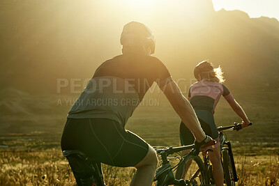 Buy stock photo Shot of a man and woman riding their bicycles in the countryside