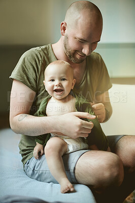 Buy stock photo Father, baby and bedroom portrait with love, clothes and smile for happiness, care or bonding in home. Dad, infant child and t-shirt for happy kid, helping hand or together on bed in morning at house