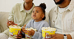 Child, parents and watching tv with popcorn on sofa for entertainment or online streaming in home. Mom, dad or kid eating snacks with daughter for movie, subscription or network service in house