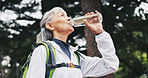 Hiking, drinking water and senior woman in nature for trekking, fitness and exercise for health. Rest, mountain and person with hydration, wellness and thirsty for trip, backpacking or travel outdoor