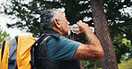 Hiking, drinking water and senior man in nature for trekking, fitness and exercise for wellness outdoor. Rest, mountain and person with hydration, health and thirsty for trip, backpacking and travel