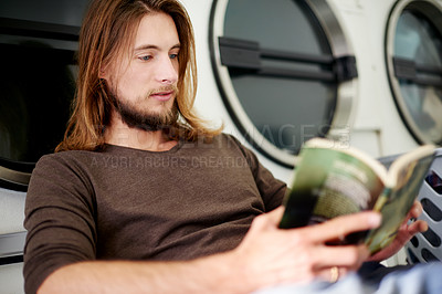 Buy stock photo Man, washing and reading a book in laundry room for cleaning service, knowledge and fabric disinfection. Hygiene, male cleaner and literature novel in laundromat for weekly tasks, routine or learning