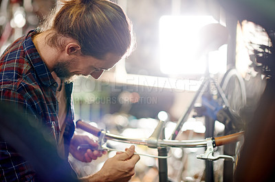 Buy stock photo Industry, repairs and man with fixing bicycle in garage for maintenance on wheels, chain or frame. Small business, service and male mechanic with tightening mechanical part on bike at workshop.