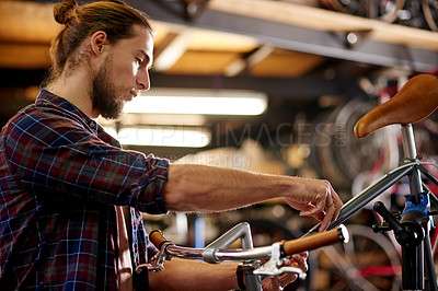 Buy stock photo Tools, repairs and man with fixing bicycle in garage for maintenance on wheels, chain or frame. Small business, service and male mechanic with tightening mechanical part on bike at workshop.