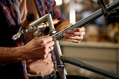 Buy stock photo Hands, bicycle repair and cable at workshop for brakes, safety and restoration services at small business. Person, bike technician or mechanic with equipment, fix and job with maintenance at garage