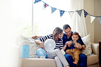 Buy stock photo Family, toys and birthday with parents and toddler in living room for celebration, love and milestone at home. Happiness, together and man with woman and child for party decorations and presents