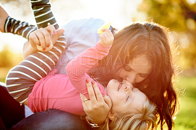 Buy stock photo Mother, girl and kiss on grass at park for game, laugh or happy with play, hug and bonding in summer. People, mom and child with care, connection and love with smile outdoor on ground in Argentina