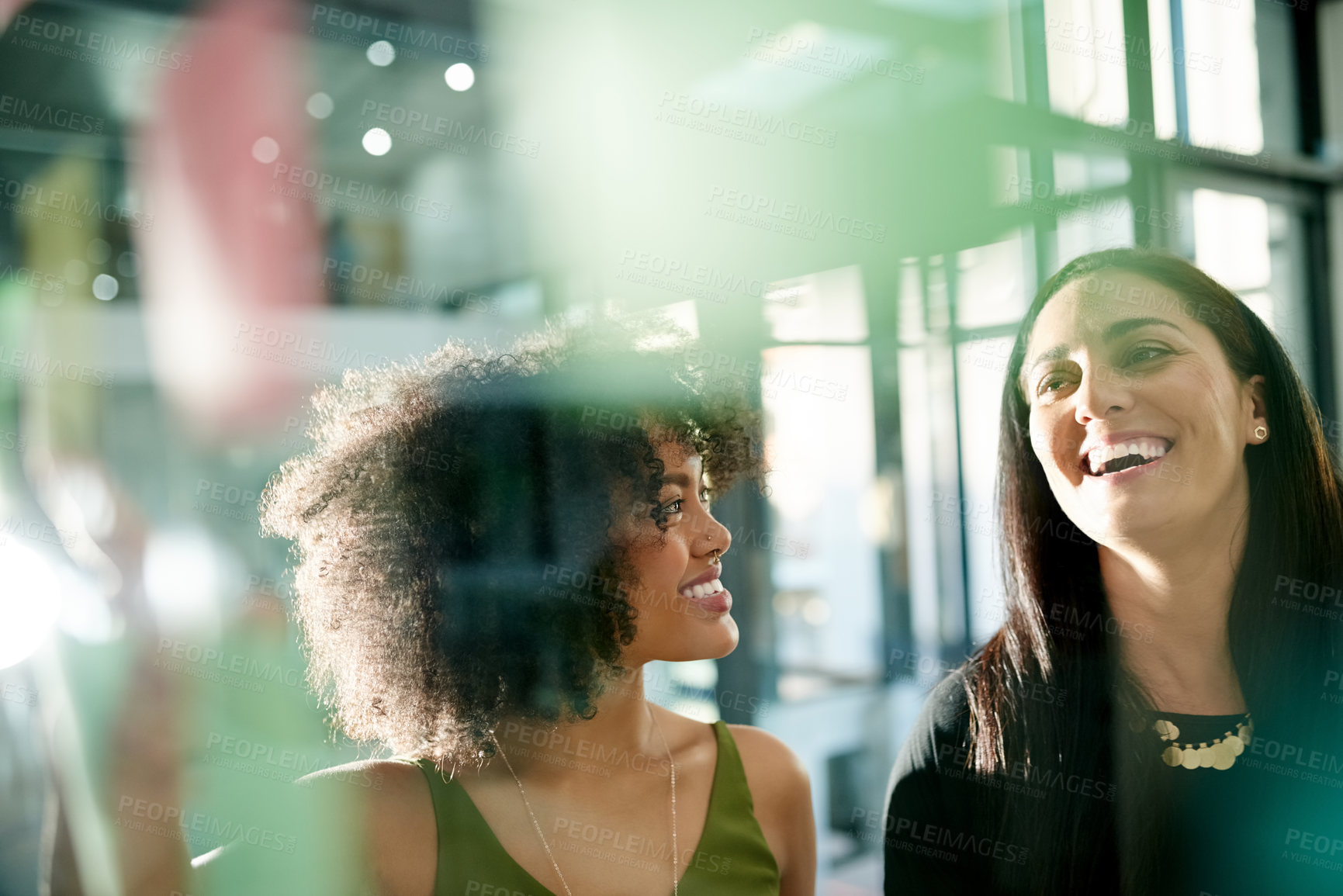 Buy stock photo Happy woman, team and laugh at glass wall, office and planning with brainstorming at media company. People, partner and talk at startup with problem solving, review and feedback at creative agency