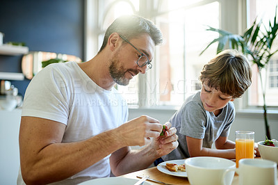 Buy stock photo Breakfast, eating and father with child in kitchen in home with bonding, connection and wellness. Orange juice, fruit and dad with boy kid for enjoying healthy morning meal together in apartment.