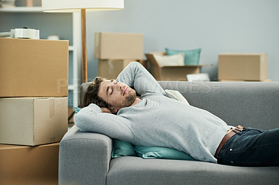 Buy stock photo Man, new home and relief on sofa, boxes and tired with smile for moving in living room at property. Person, happy and relax for rest, fatigue or sleeping on couch for fresh start with real estate
